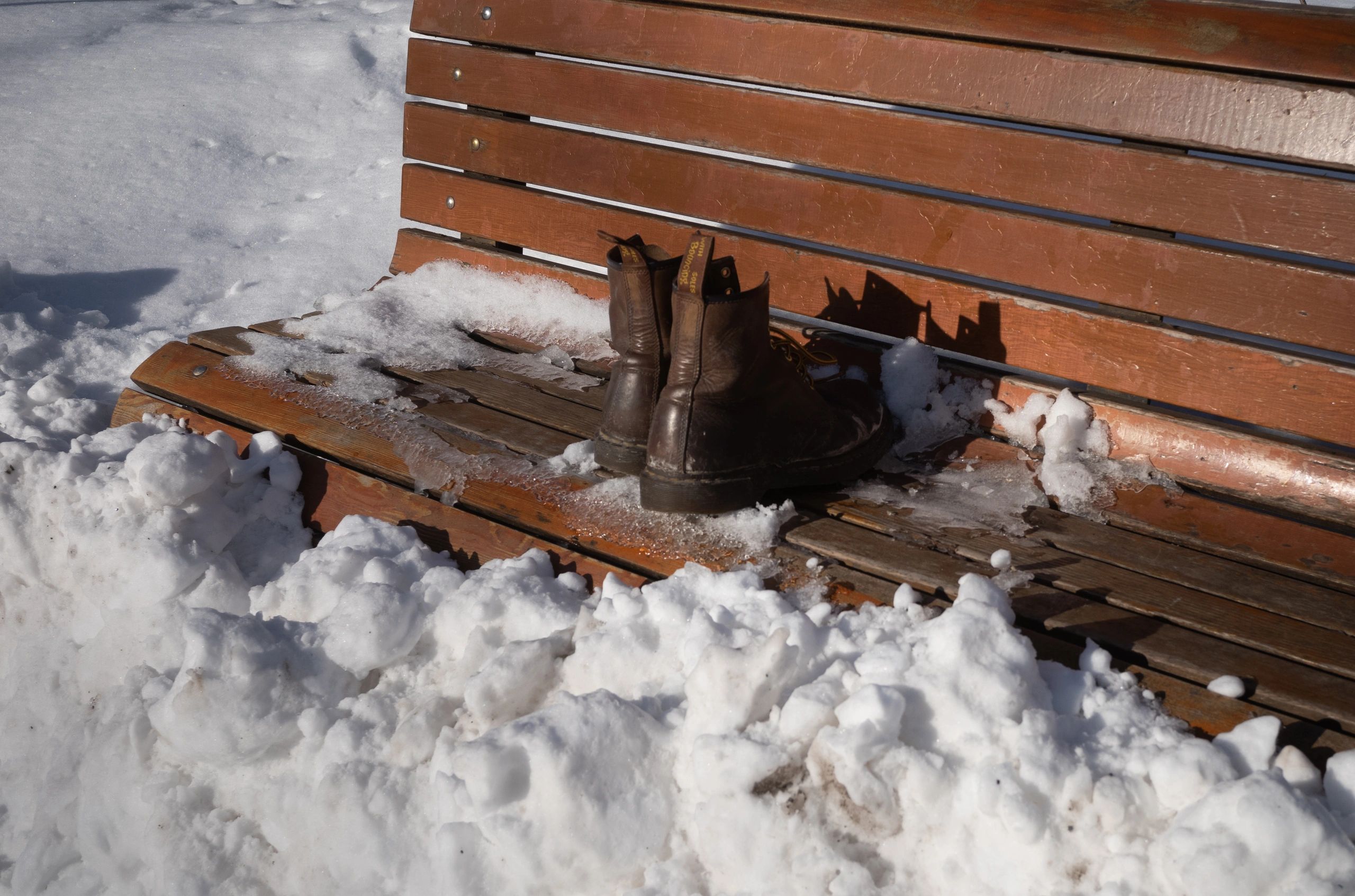 Pair of boots displayed outdoors on a wooden bench